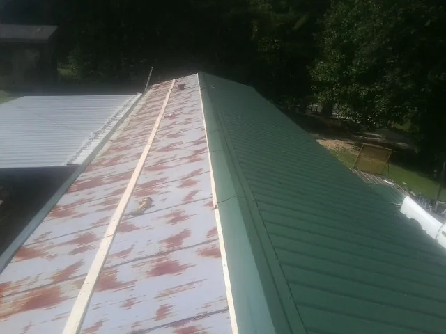 Old rusted panels beside newly installed green metal roofing — Wind Damage Roof Repair by Roofing Brothers in Oriskany