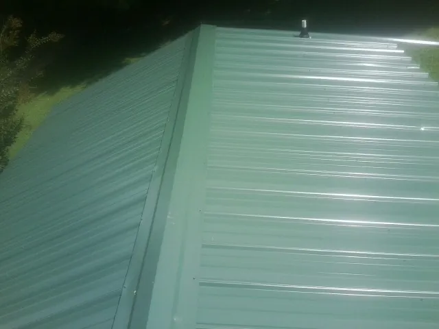 New green metal panels meeting at the ridge of a roof — Flat Roof Repair work by our crew in Oriskany
