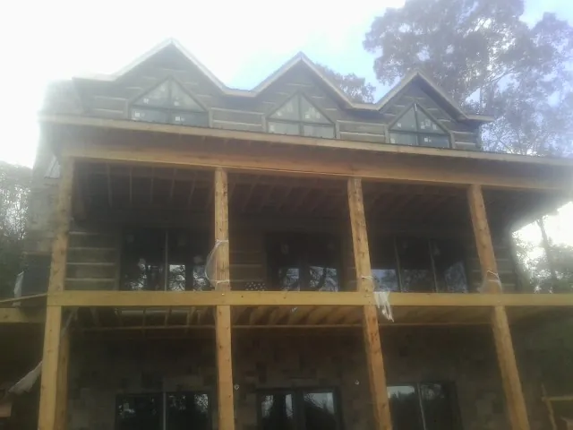 Dormers and porch framing on a large log home under construction — Roof Coating work by our crew in Oriskany