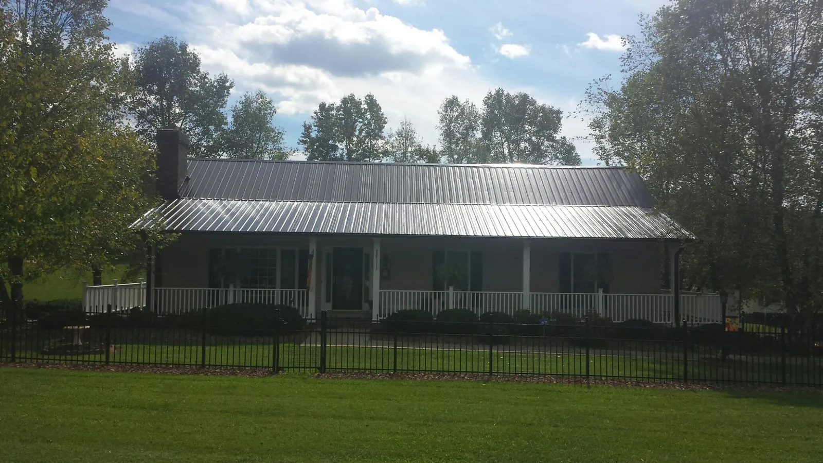 Gray metal roof on a brick ranch with a full width front porch — Gutter Guard Installation work by our crew in Oriskany
